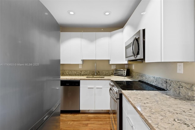 kitchen featuring recessed lighting, light wood-style flooring, white cabinetry, stainless steel appliances, and a sink