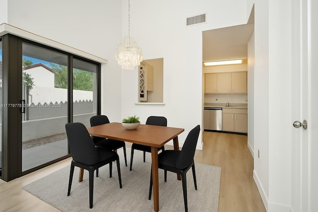 331 Ives Dairy Rd Unit 331-09, Miami, FL 33179 - dining space featuring a towering ceiling, light wood-style floors, a chandelier, and baseboards