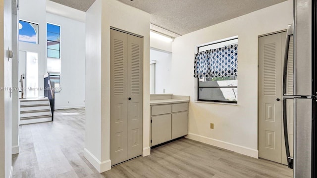 331 Ives Dairy Rd Unit 331-09, Miami, FL 33179 - hallway with light wood finished floors, baseboards, a textured ceiling, and stairs