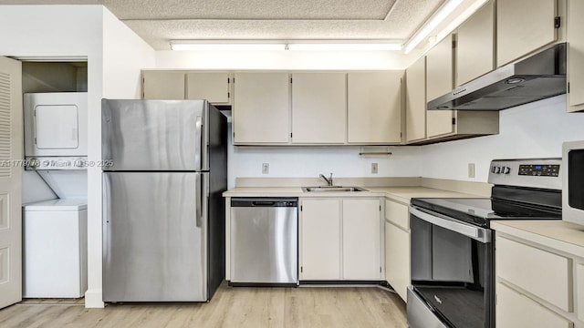 331 Ives Dairy Rd Unit 331-09, Miami, FL 33179 - kitchen featuring stainless steel appliances, stacked washing machine and dryer, under cabinet range hood, light wood-style floors, and a sink