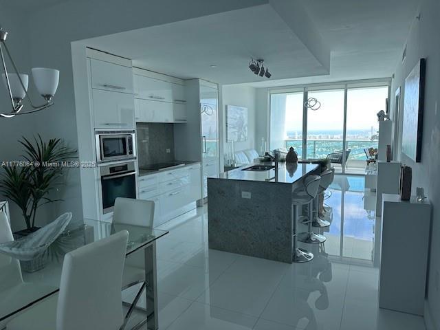 kitchen with stainless steel appliances, white cabinets, modern cabinets, a sink, and a kitchen bar