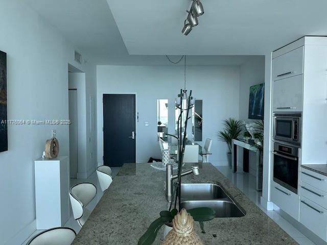 kitchen featuring stainless steel appliances, light stone countertops, a sink, and modern cabinets