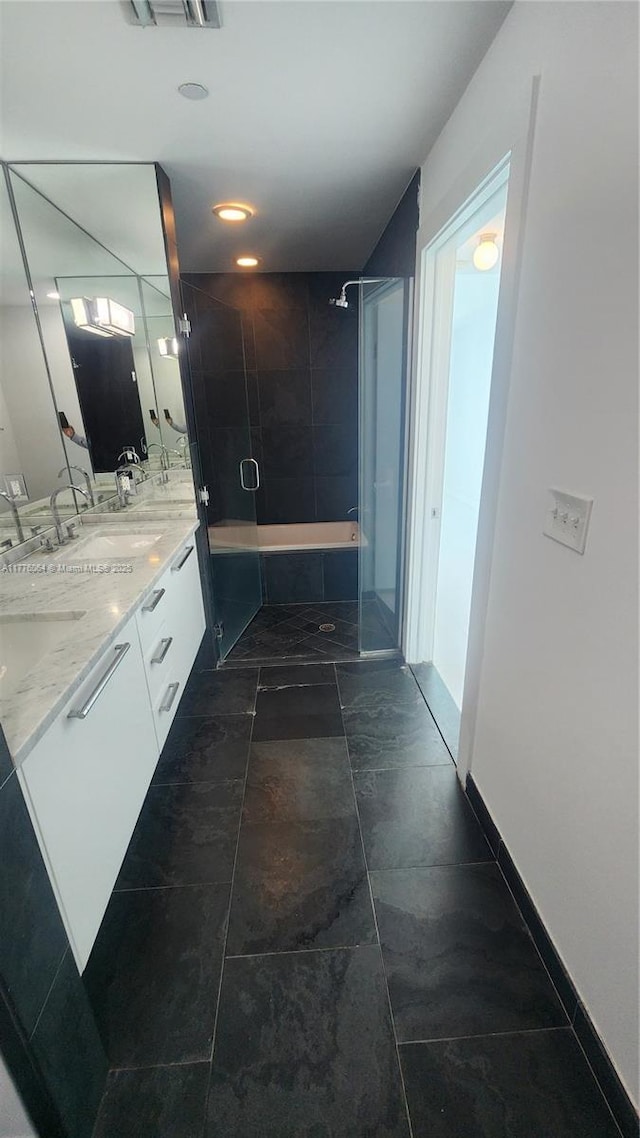 full bathroom featuring a shower with shower door, a tub, and double vanity