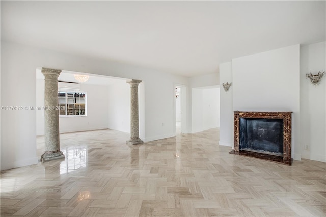 unfurnished living room featuring baseboards, a fireplace, and ornate columns