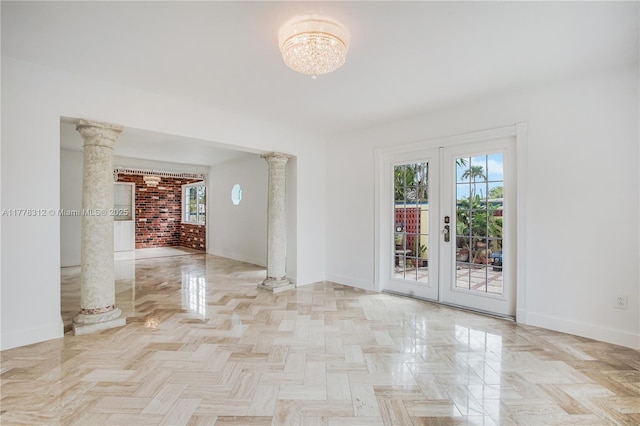 unfurnished room with a chandelier, baseboards, ornate columns, and french doors