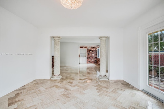 spare room with baseboards, ornate columns, and a notable chandelier