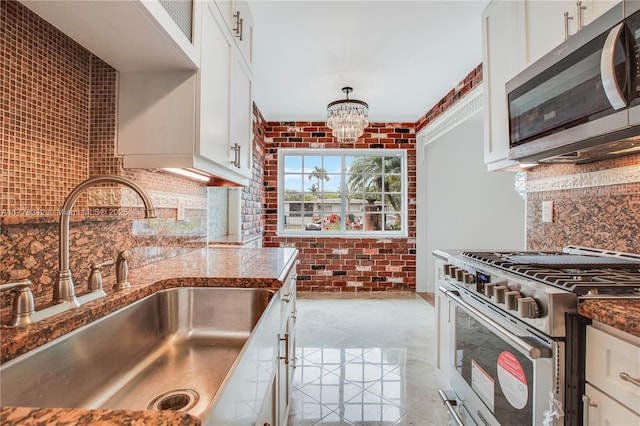 kitchen featuring stainless steel appliances, a sink, backsplash, and dark stone counters