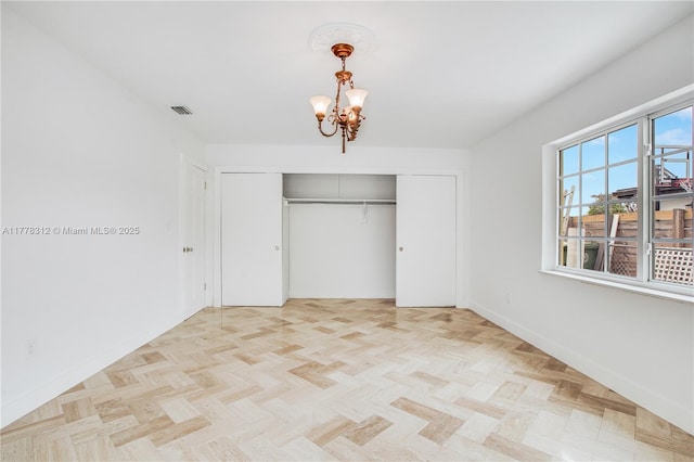 unfurnished bedroom featuring a closet, baseboards, and a notable chandelier