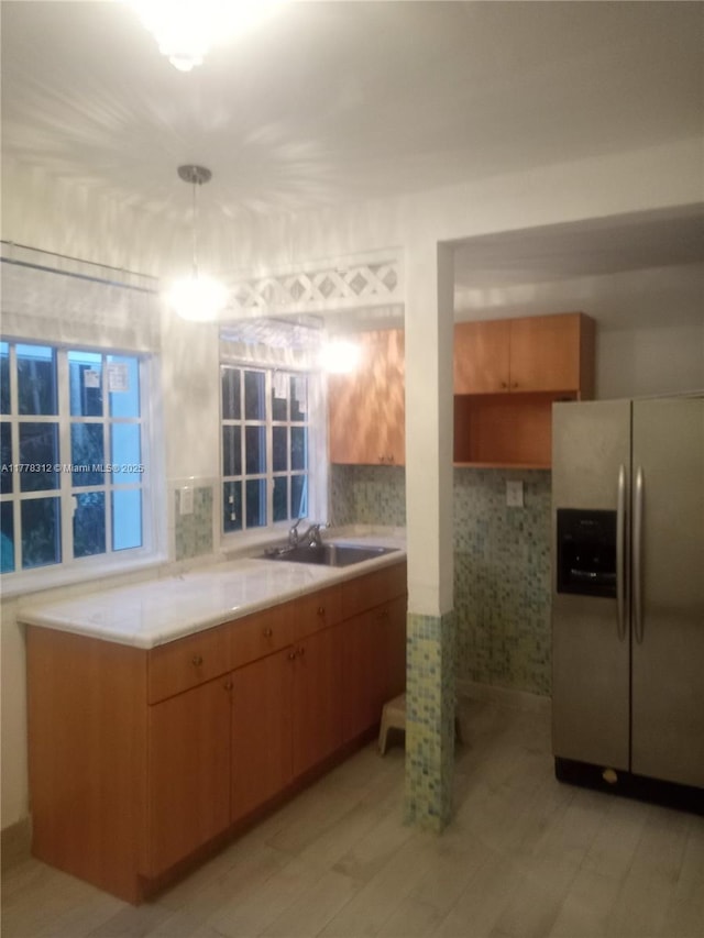kitchen with light countertops, decorative light fixtures, a sink, and stainless steel fridge with ice dispenser
