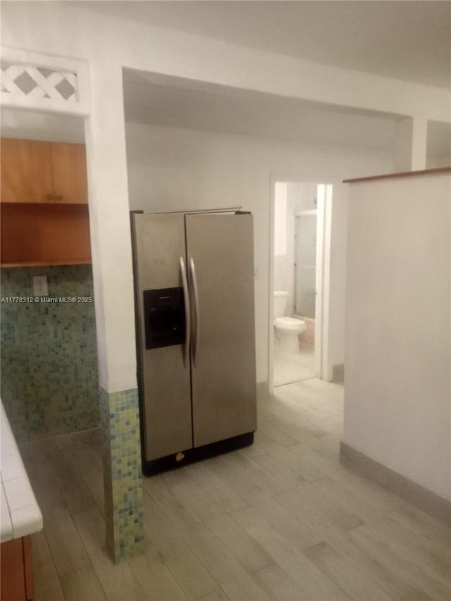 kitchen featuring light wood finished floors, stainless steel refrigerator with ice dispenser, and tile counters