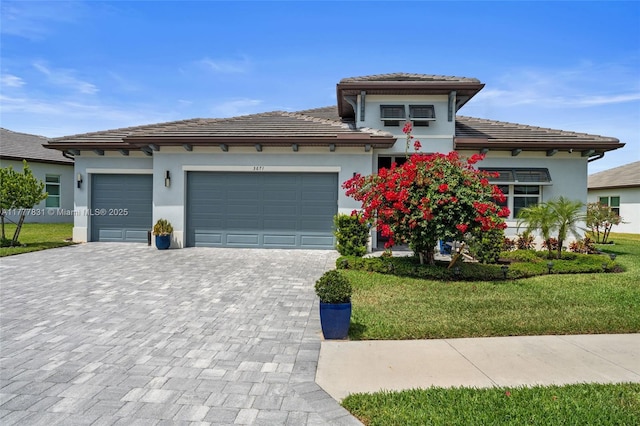 prairie-style house with a front yard, a tiled roof, a garage, stucco siding, and decorative driveway