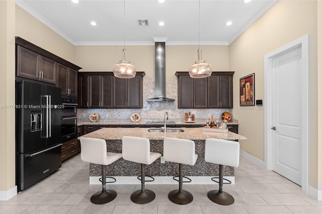 kitchen with black appliances, a kitchen breakfast bar, wall chimney exhaust hood, and dark brown cabinetry