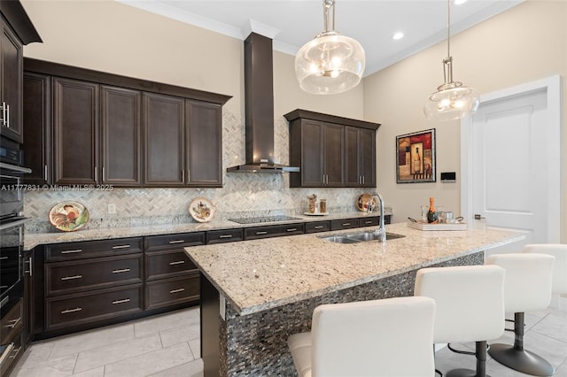 kitchen featuring tasteful backsplash, a sink, wall chimney range hood, a kitchen breakfast bar, and black electric stovetop