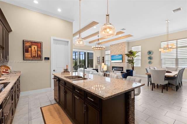 kitchen with hanging light fixtures, a sink, dark brown cabinetry, a large fireplace, and stainless steel dishwasher
