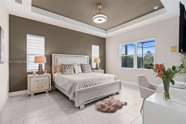 bedroom with a tray ceiling, baseboards, light tile patterned flooring, and visible vents