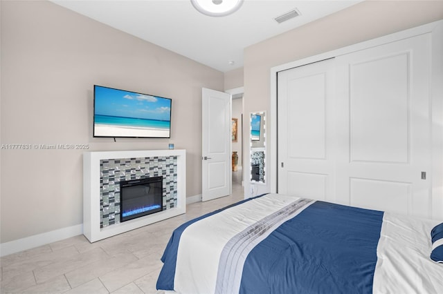 bedroom featuring a closet, baseboards, a tiled fireplace, visible vents, and marble finish floor