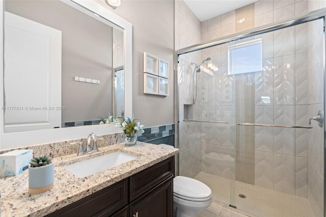 bathroom featuring toilet, a stall shower, and vanity