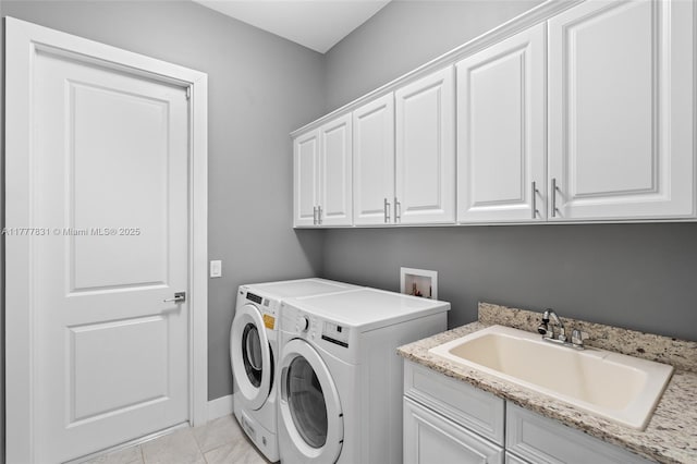 washroom with cabinet space, baseboards, separate washer and dryer, and a sink