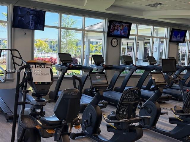 gym featuring a tray ceiling, visible vents, and wood finished floors