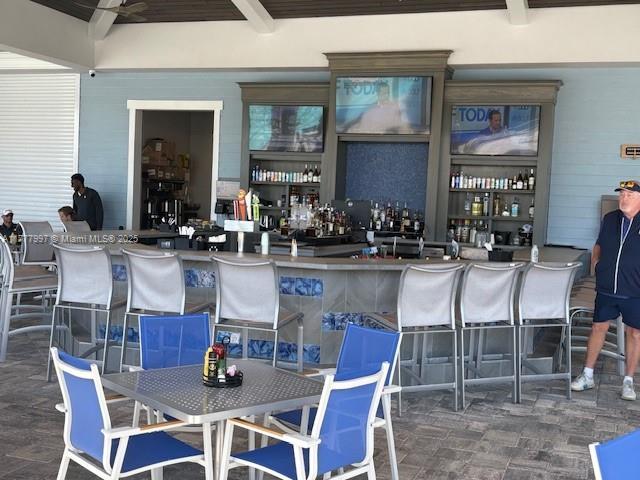 bar featuring beamed ceiling and a dry bar