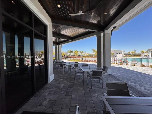 view of patio featuring a ceiling fan, fence, and outdoor dining space