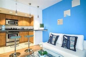 7326 Collins Ave Unit 102, Miami Beach, FL 33141 - kitchen with appliances with stainless steel finishes, dark countertops, brown cabinetry, and pendant lighting
