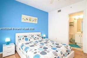 7326 Collins Ave Unit 102, Miami Beach, FL 33141 - bedroom with light wood finished floors, connected bathroom, and a ceiling fan