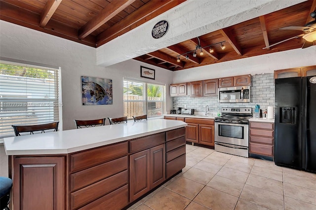 108 Long Ben Dr, Key Largo, FL 33037 - kitchen with beamed ceiling, wood ceiling, light countertops, stainless steel appliances, and backsplash