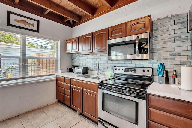 108 Long Ben Dr, Key Largo, FL 33037 - kitchen featuring light countertops, backsplash, light tile patterned flooring, beamed ceiling, and appliances with stainless steel finishes