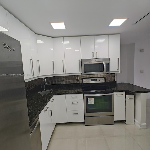 2750 NE 183rd St Unit 301, Aventura, FL 33160 - kitchen featuring tasteful backsplash, white cabinetry, dark stone countertops, appliances with stainless steel finishes, and a sink