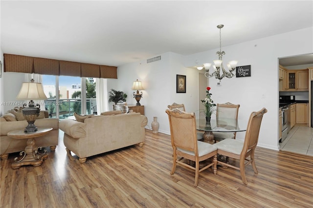 dining area featuring visible vents, baseboards, light wood-type flooring, and a chandelier