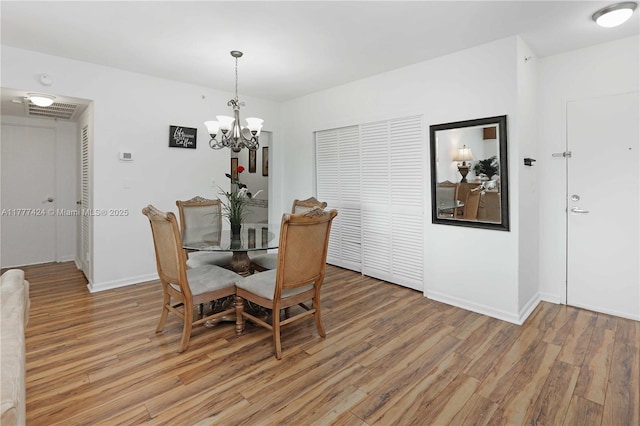dining room featuring a notable chandelier, baseboards, and light wood-style flooring
