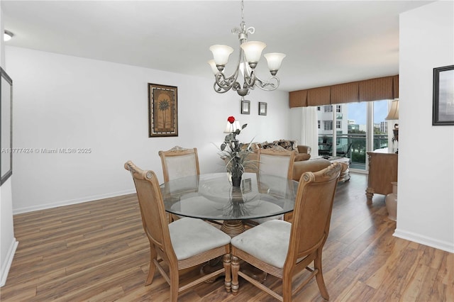 dining space with a chandelier, wood finished floors, and baseboards