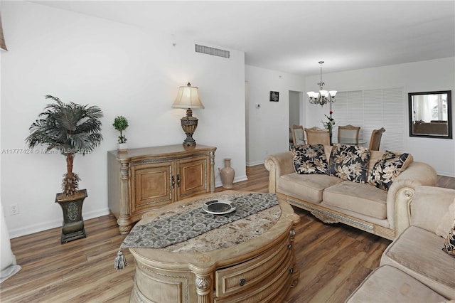 living room featuring visible vents, baseboards, a chandelier, and light wood-style floors