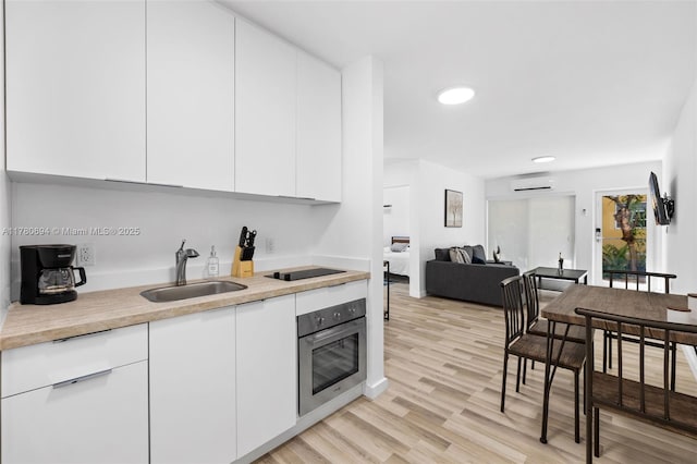 kitchen with modern cabinets, a sink, white cabinetry, and stainless steel oven