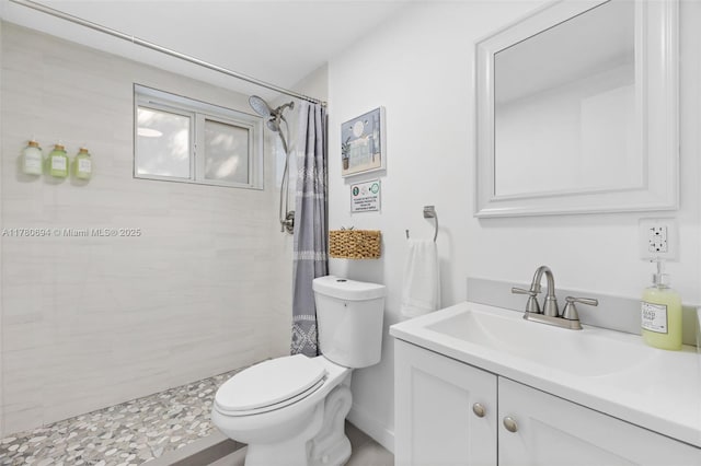 bathroom with toilet, tiled shower, and vanity