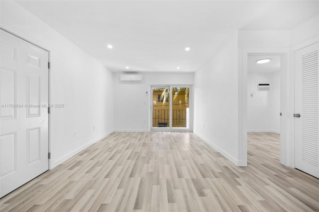 empty room with light wood-style flooring, recessed lighting, an AC wall unit, a wall mounted air conditioner, and baseboards