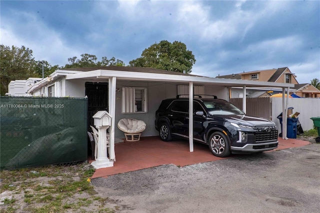 view of vehicle parking with fence and an attached carport