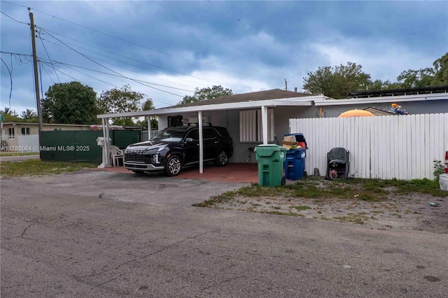 view of car parking featuring aphalt driveway and fence