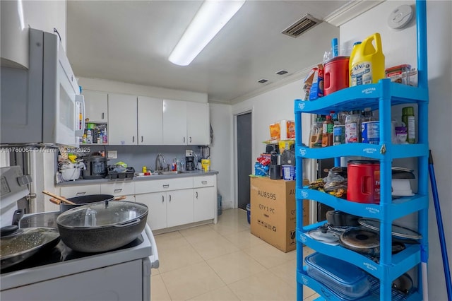 kitchen with light tile patterned floors, light countertops, white cabinetry, visible vents, and a sink
