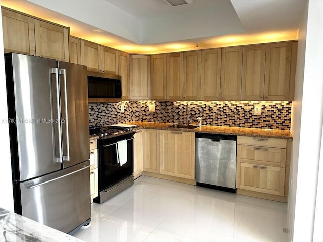 kitchen with tasteful backsplash, light stone countertops, stainless steel appliances, and a sink
