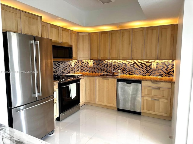 kitchen featuring light stone counters, backsplash, appliances with stainless steel finishes, and a sink