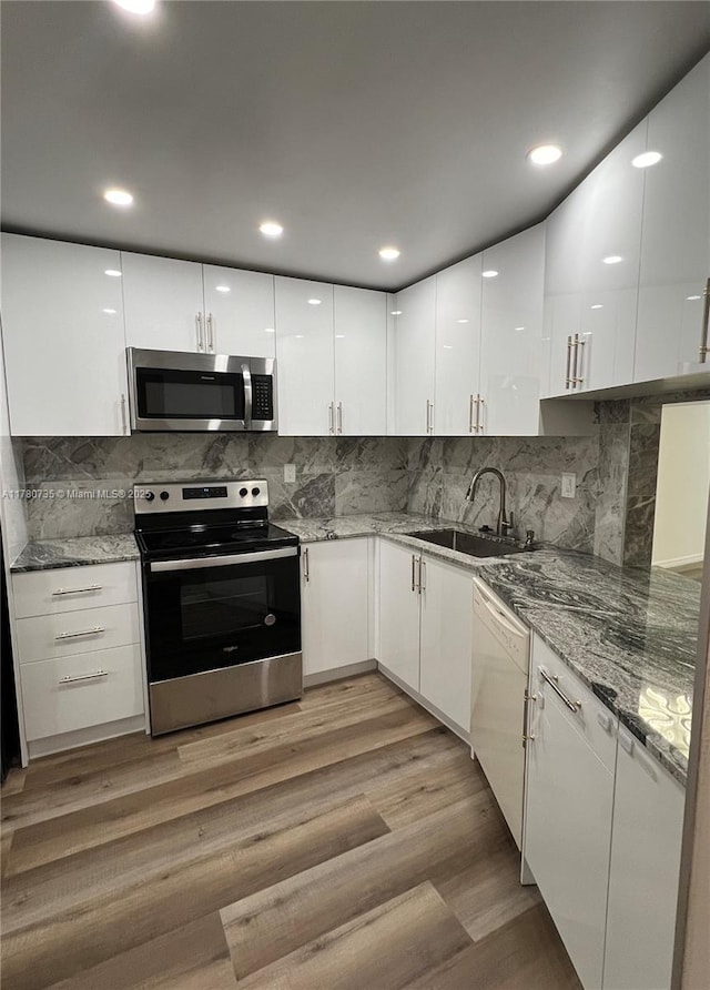 kitchen featuring stainless steel appliances, white cabinets, modern cabinets, and a sink