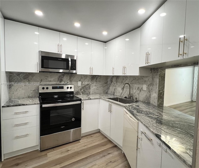 kitchen featuring a sink, appliances with stainless steel finishes, white cabinetry, and modern cabinets