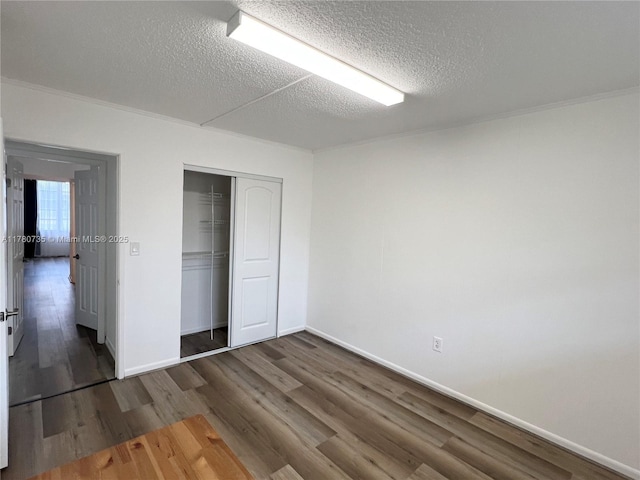 unfurnished bedroom with a closet, baseboards, wood finished floors, and a textured ceiling