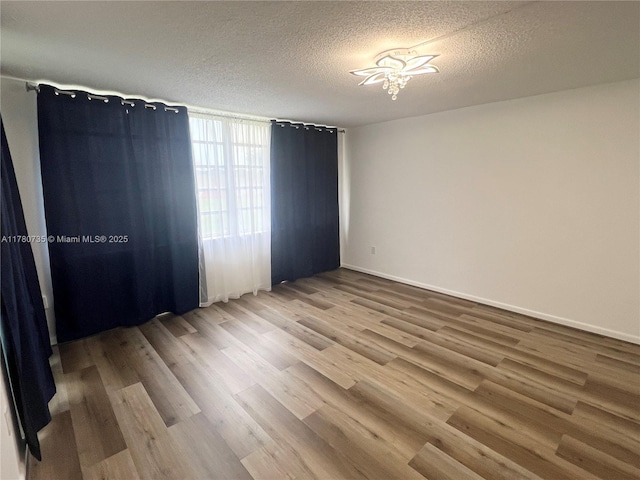 empty room featuring a textured ceiling and wood finished floors