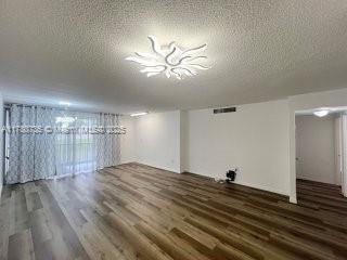 interior space with a textured ceiling and wood finished floors