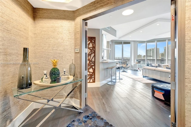 interior space with wood finished floors, a view of city, floor to ceiling windows, and recessed lighting