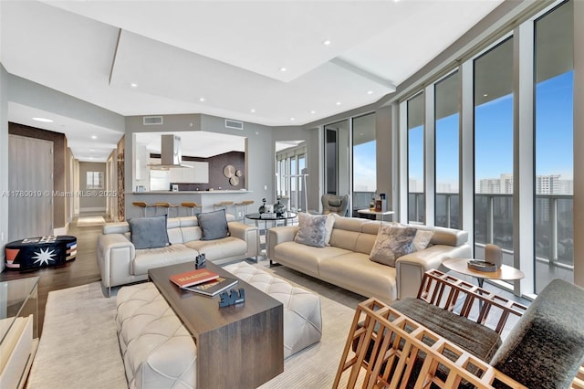 living room with floor to ceiling windows, recessed lighting, light wood finished floors, and visible vents