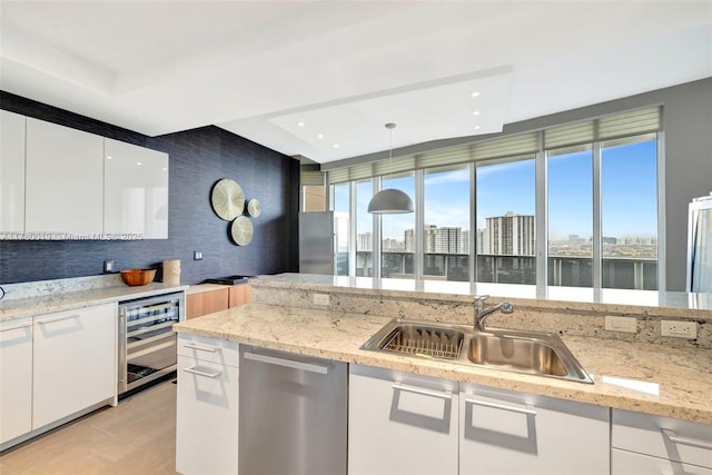 kitchen with dishwasher, modern cabinets, a sink, beverage cooler, and a city view